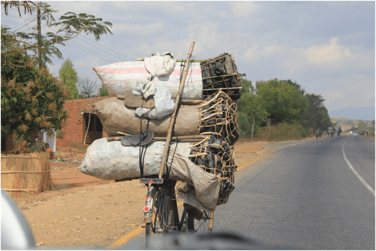 Eenzame fietser met zakken houtskool in Malawi